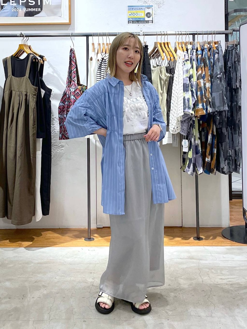 グレー系のスカート、ホワイト系のサンダル、ホワイト系のTシャツ/カットソーを着用したレディースの夏コーディネートの1枚目の写真