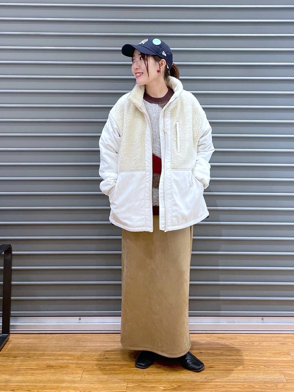 ホワイト系のその他アウター、ベージュ系のスカート、ブラウン系のニット/セーターを着用したレディースの秋コーディネートの1枚目の写真