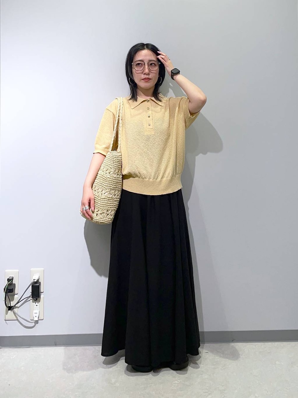 ブラック系のスカート、ブラック系のサンダル、ベージュ系のトートバッグを着用したレディースの春コーディネートの1枚目の写真