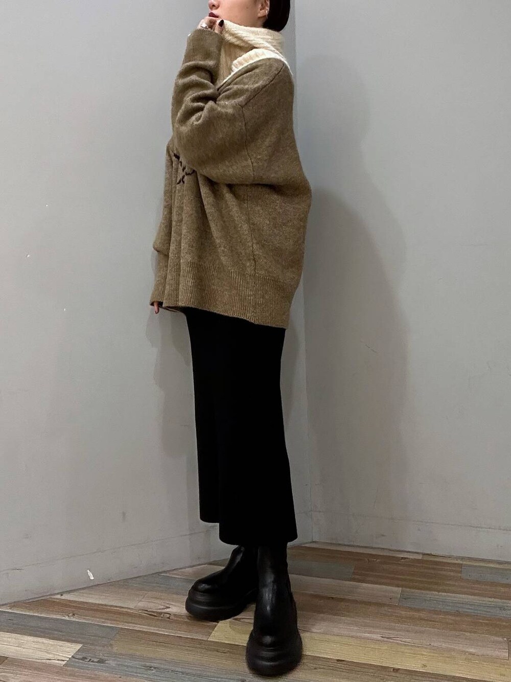 ブラック系のブーツ、ブラック系のスカート、ベージュ系のニット/セーターを着用したレディースの冬コーディネートの1枚目の写真