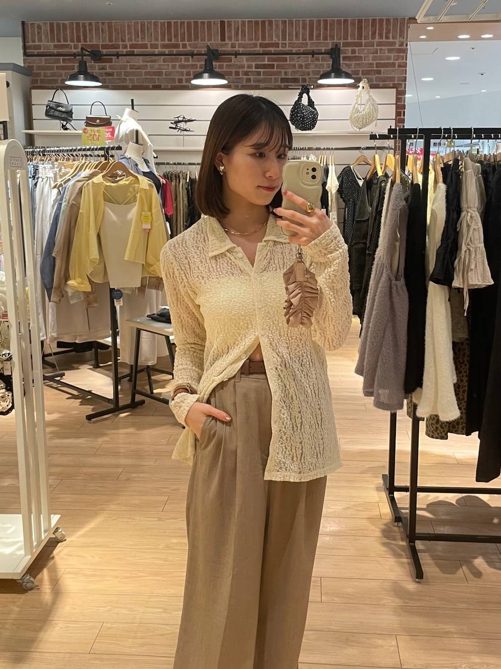 ベージュ系のスラックス、ホワイト系のTシャツ/カットソー、ベージュ系のチョーカーを着用したレディースの夏コーディネートの1枚目の写真