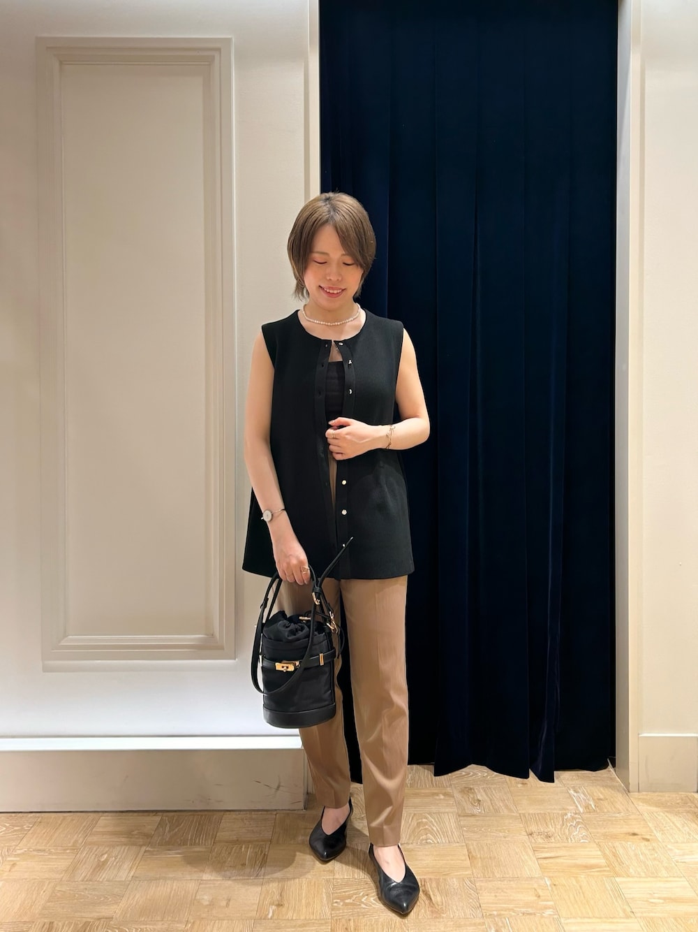 ブラック系のベスト、ブラック系のショルダーバッグ、イエロー系のその他パンツを着用したレディースの秋コーディネートの1枚目の写真