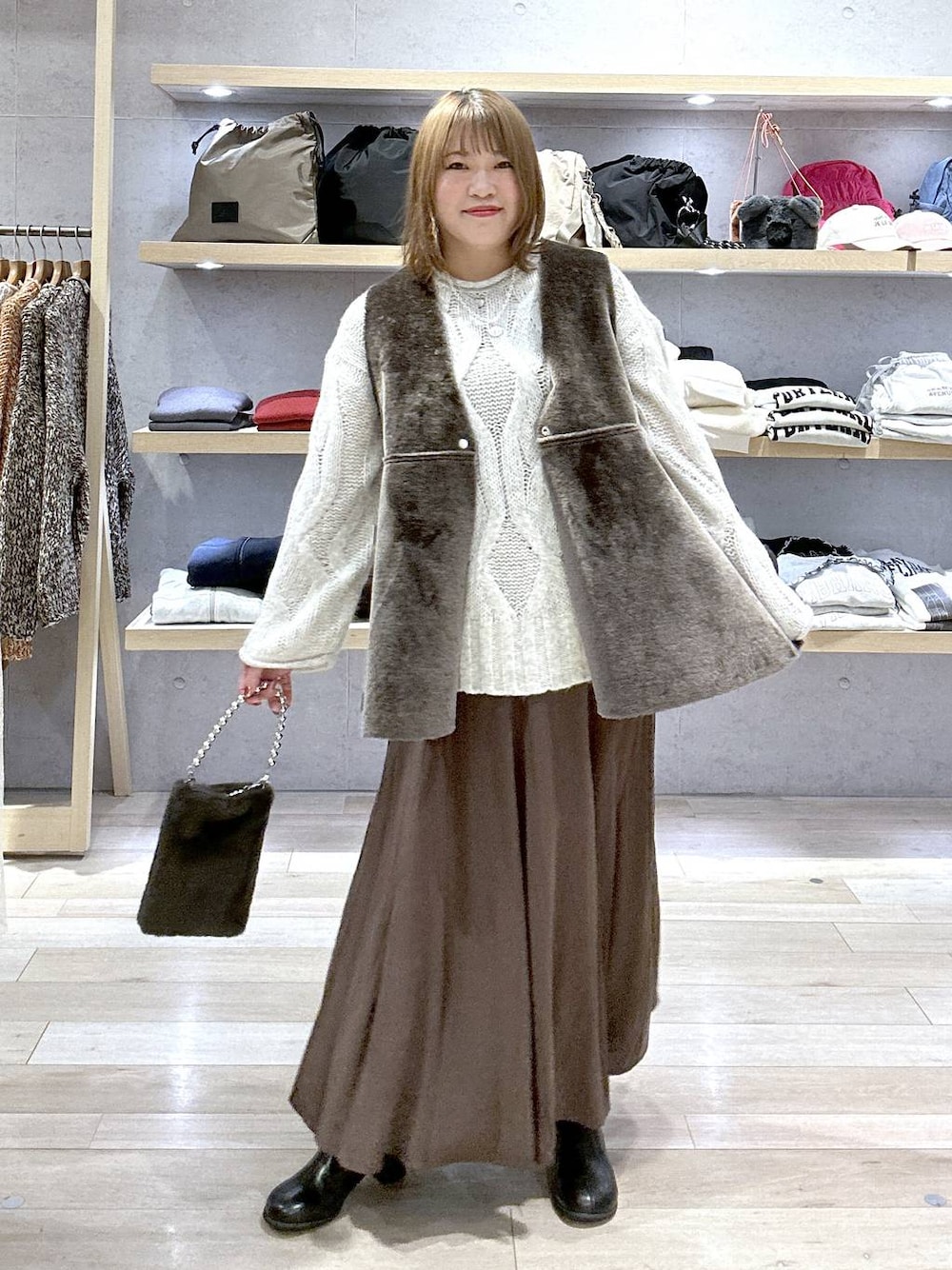 グレー系のニット/セーター、ブラック系のブーツ、グレー系のショルダーバッグを着用したレディースの冬コーディネートの1枚目の写真