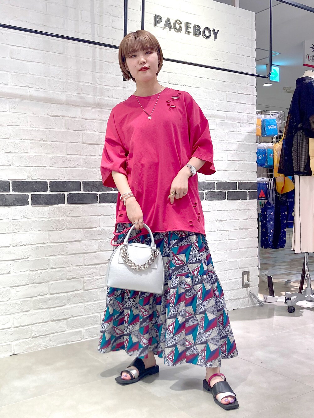 シルバー系のショルダーバッグ、ピンク系のTシャツ/カットソー、ホワイト系のスカートを着用したレディースの春コーディネートの1枚目の写真