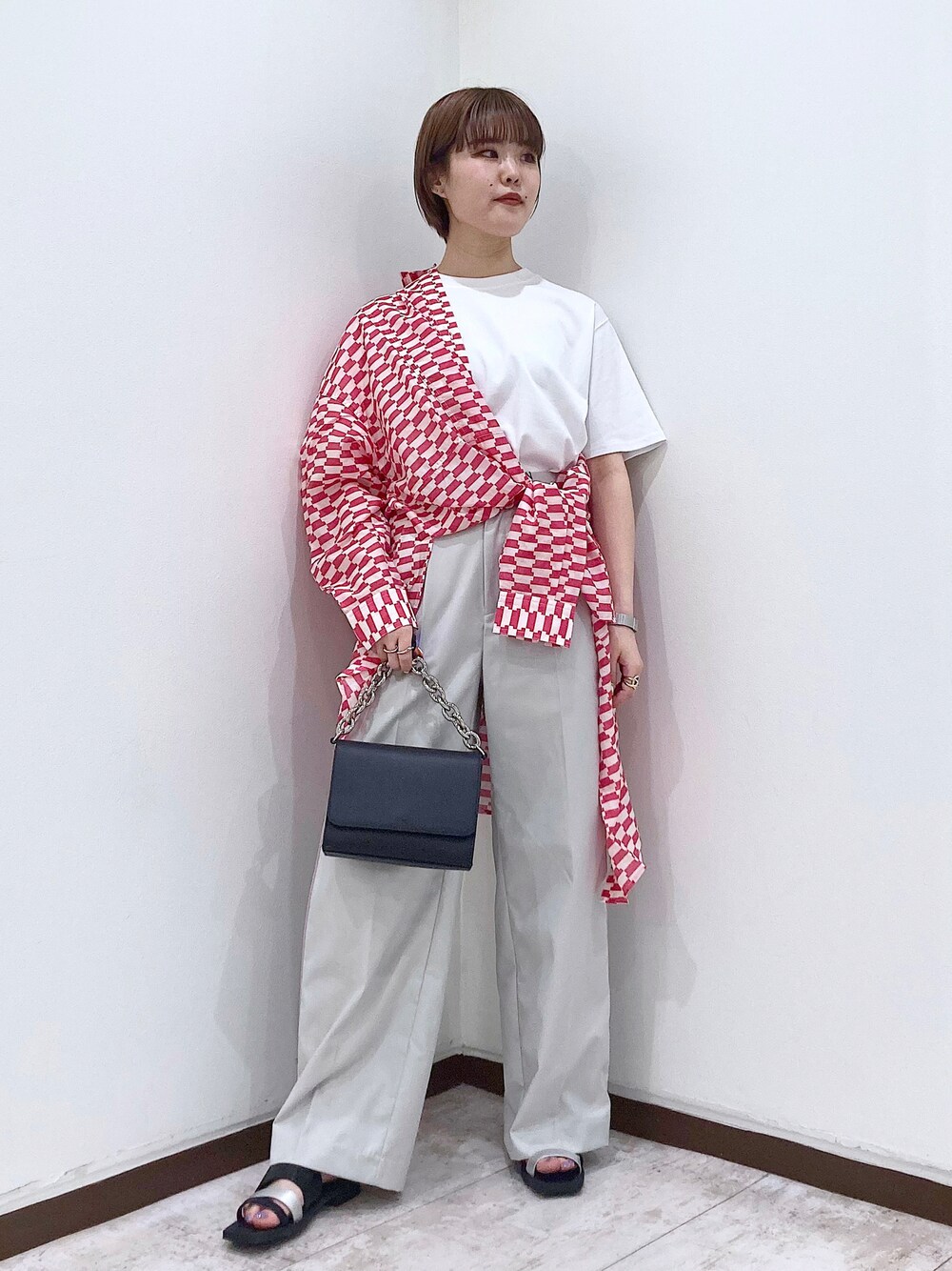 ブラック系のショルダーバッグ、ベージュ系のスラックス、オレンジ系のシャツ/ブラウスを着用したレディースの春コーディネートの1枚目の写真