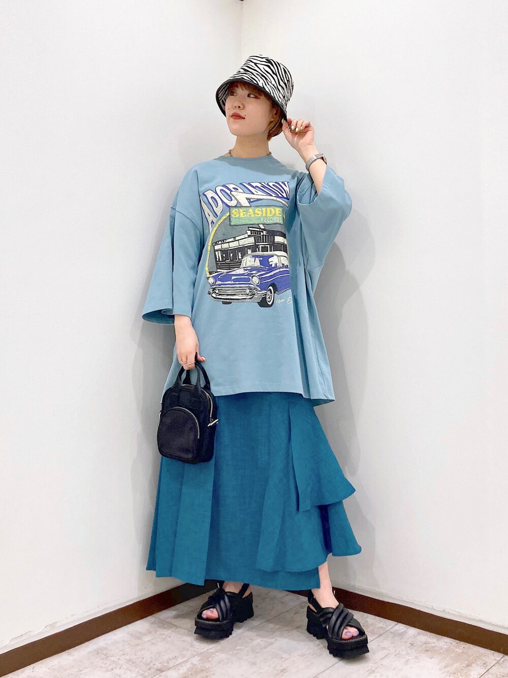 ブルー系のTシャツ/カットソー、ブラック系のショルダーバッグ、ブルー系のスカートを着用したレディースの春コーディネートの1枚目の写真