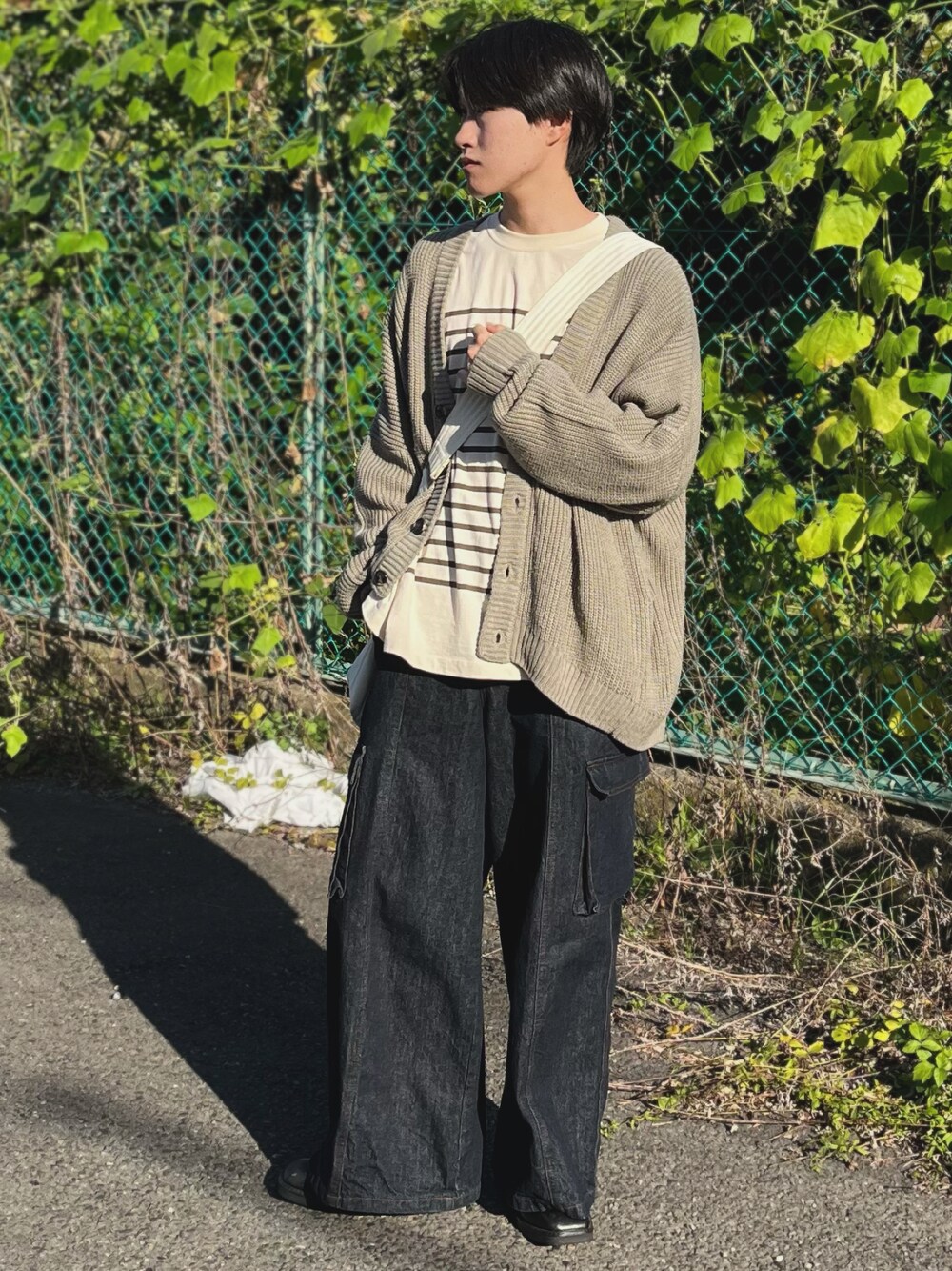 ブルー系のデニムパンツ、ベージュ系のカーディガン/ボレロ、グリーン系のTシャツ/カットソーを着用したメンズの秋コーディネートの1枚目の写真