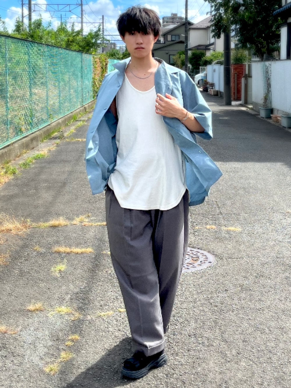 グレー系のスラックス、ブルー系のシャツ/ブラウス、ホワイト系のタンクトップを着用したメンズの夏コーディネートの1枚目の写真