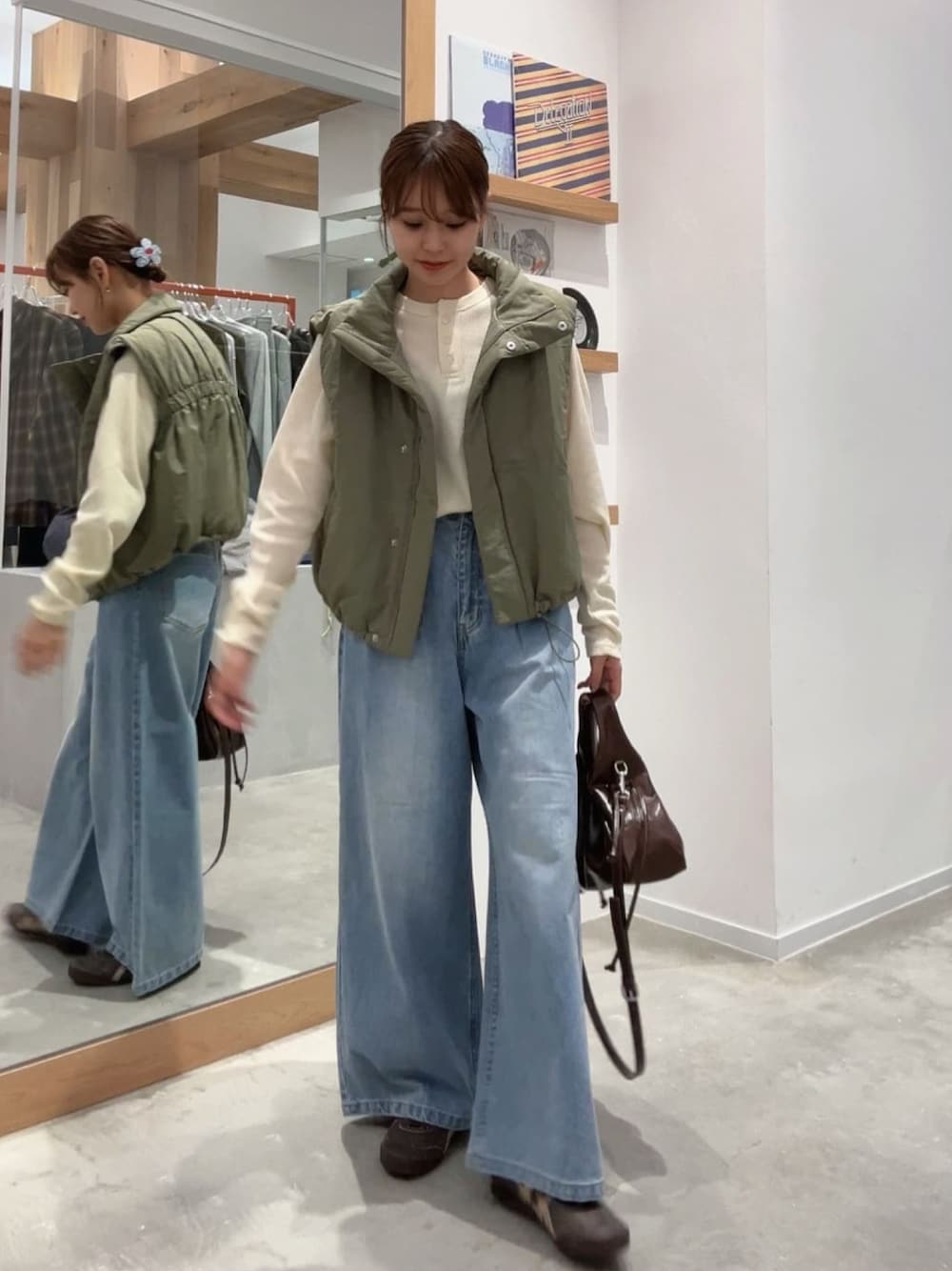 ブルー系のデニムパンツ、ホワイト系のTシャツ/カットソー、グリーン系のダウンベストを着用したレディースの秋コーディネートの1枚目の写真