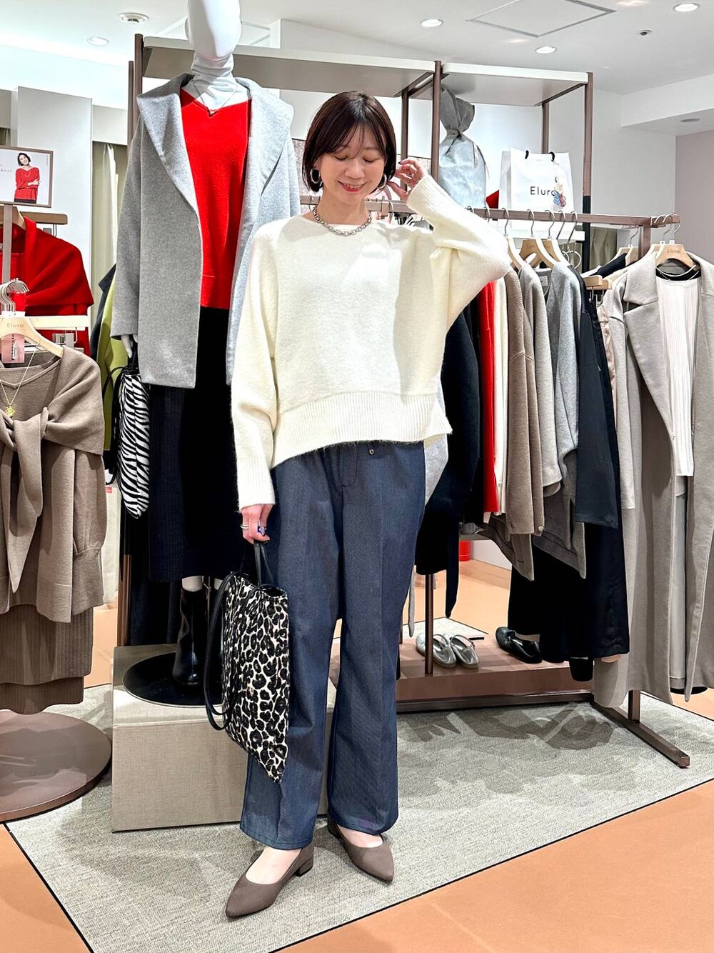 ブルー系のデニムパンツ、ホワイト系のニット/セーター、ブラウン系のパンプスを着用したレディースの冬コーディネートの1枚目の写真