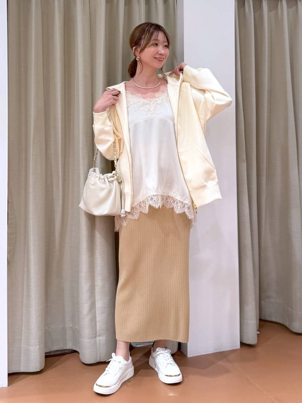 ホワイト系のハンドバッグ、ベージュ系のスカート、ホワイト系のパーカーを着用したレディースの冬コーディネートの1枚目の写真