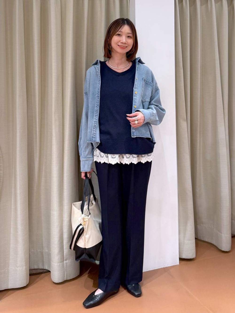 ベージュ系のトートバッグ、ブラック系のパンプス、ホワイト系のタンクトップを着用したレディースの冬コーディネートの1枚目の写真