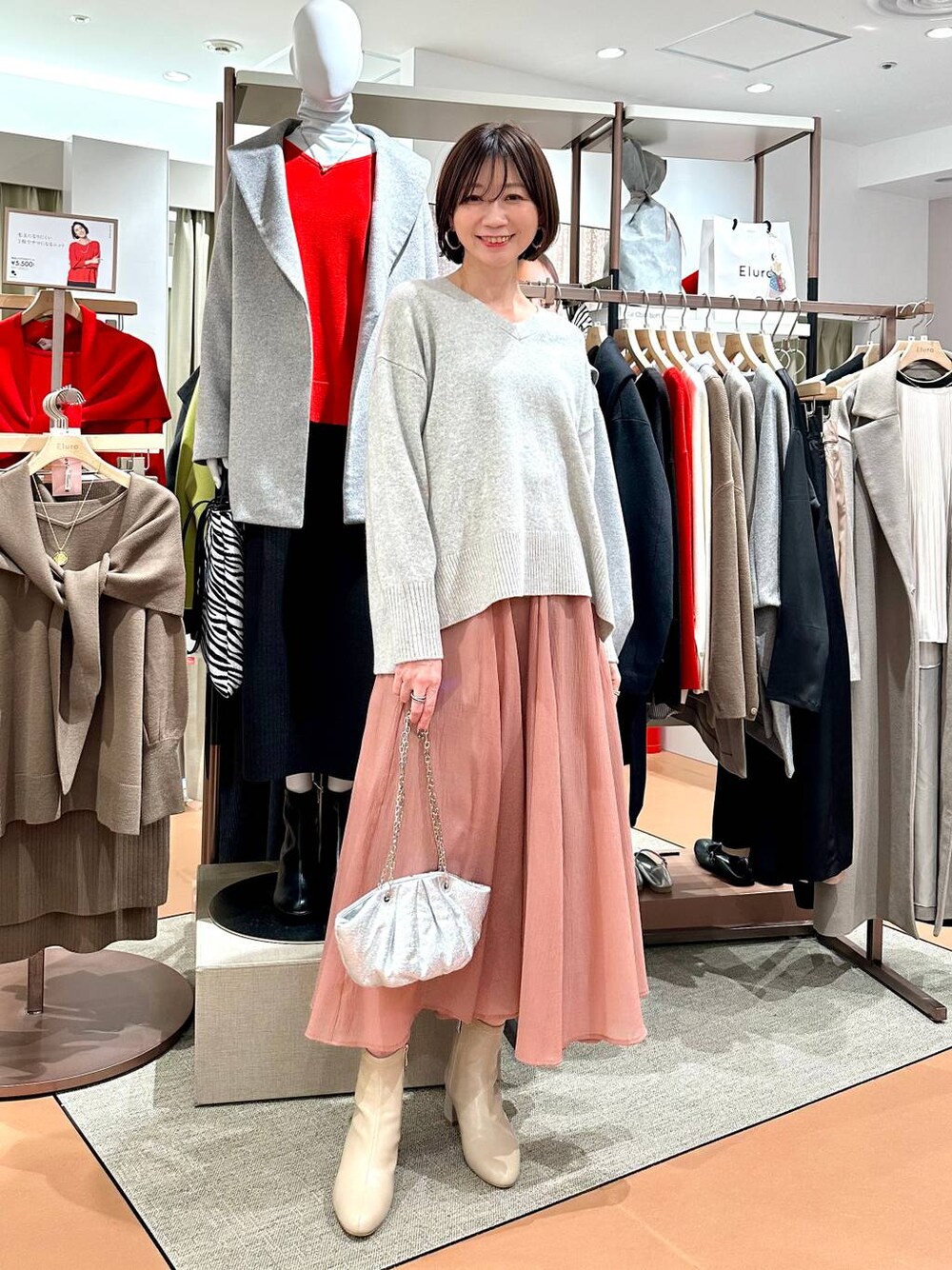 グレー系のニット/セーター、ベージュ系のブーツ、ピンク系のスカートを着用したレディースの冬コーディネートの1枚目の写真