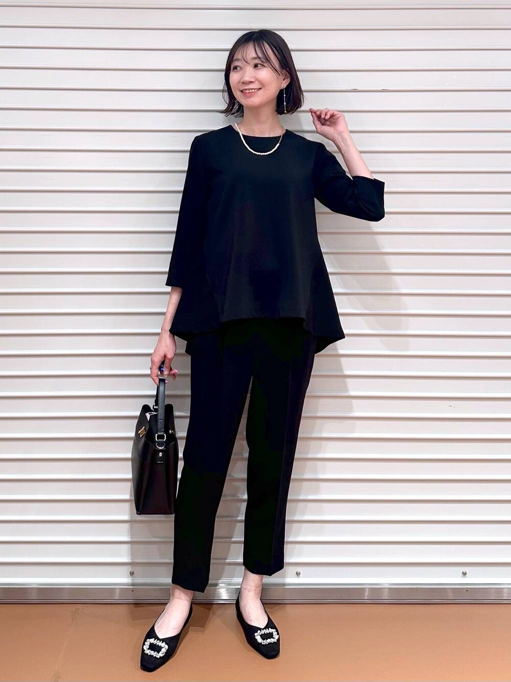 ブラック系のその他パンツ、ブラック系のシャツ/ブラウス、ブラック系のハンドバッグを着用したレディースの春コーディネートの1枚目の写真