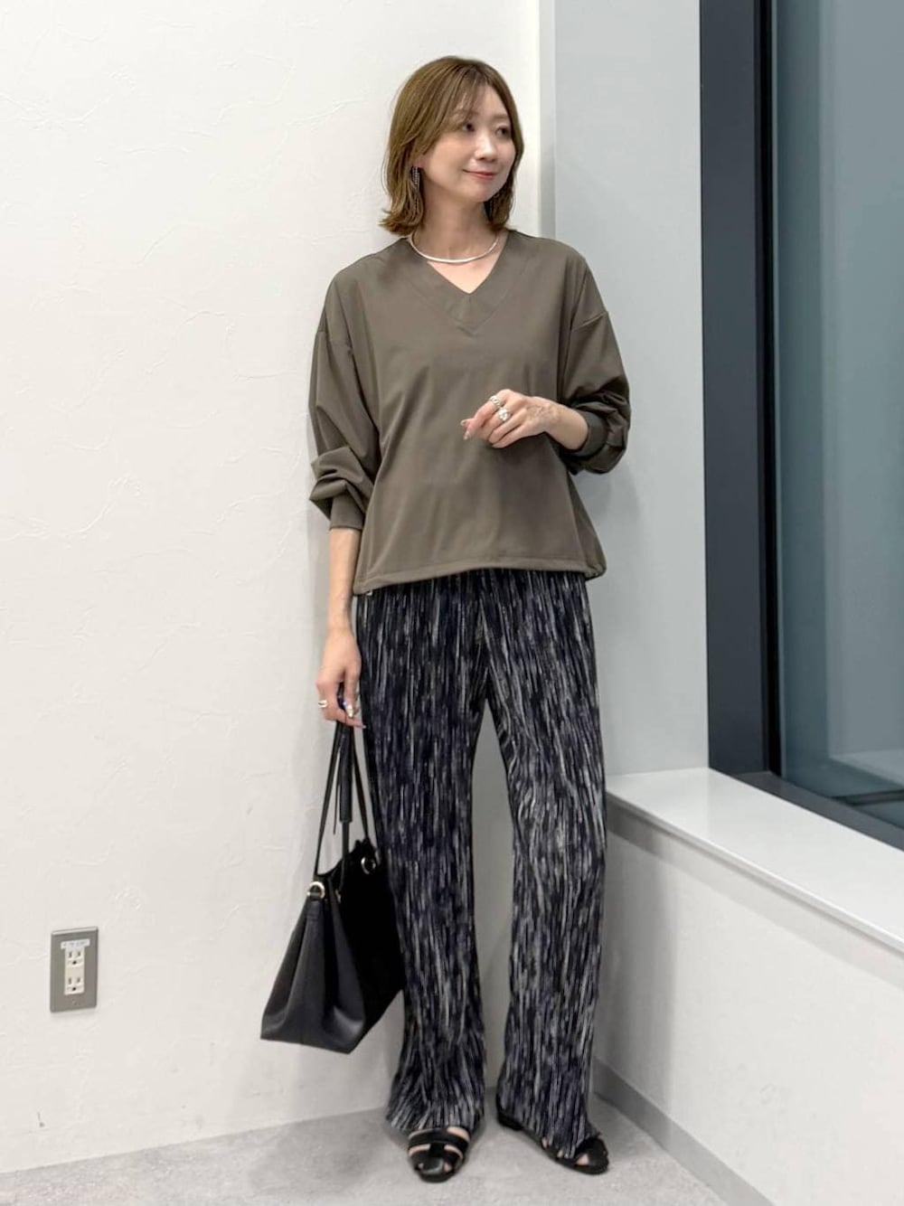 ブラック系のその他パンツ、ブラック系のトートバッグ、グリーン系のTシャツ/カットソーを着用したレディースの冬コーディネートの1枚目の写真