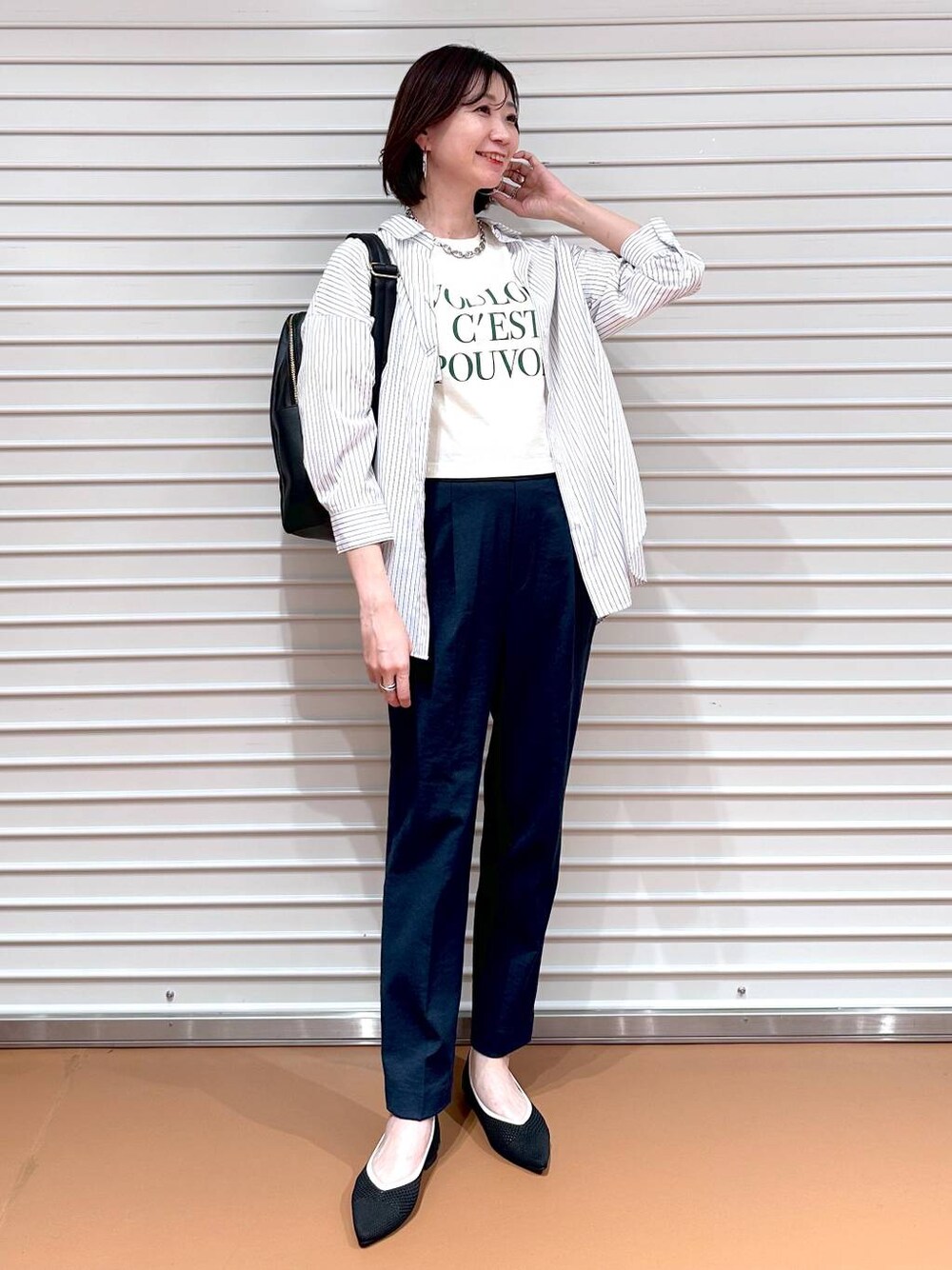 ブラック系のパンプス、ホワイト系のシャツ/ブラウス、ブラック系のバックパック/リュックを着用したレディースの春コーディネートの1枚目の写真