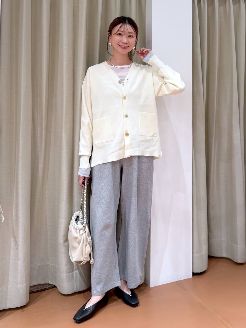 ホワイト系のカーディガン/ボレロ、ホワイト系のハンドバッグ、ブラック系のパンプスを着用したレディースの冬コーディネートの1枚目の写真