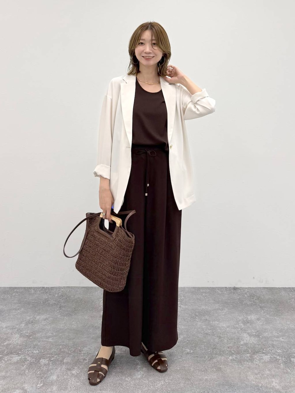 ブラウン系のパンプス、ブラウン系のその他パンツ、ホワイト系のテーラードジャケットを着用したレディースの春コーディネートの1枚目の写真