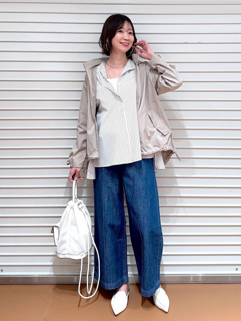 ブルー系のデニムパンツ、ホワイト系のシャツ/ブラウス、ベージュ系のマウンテンパーカーを着用したレディースの春コーディネートの1枚目の写真