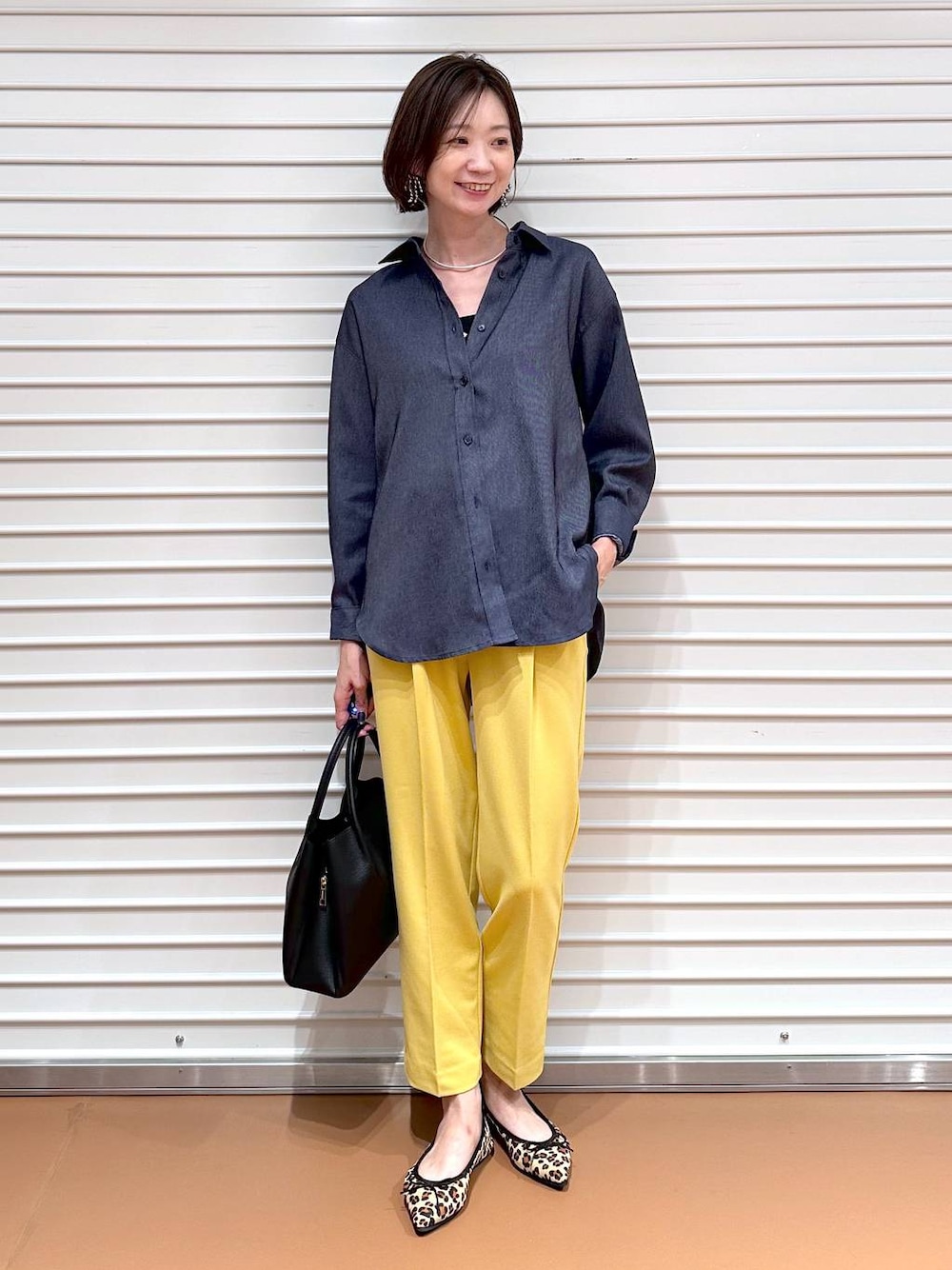 イエロー系のその他パンツ、ブラック系のハンドバッグ、ブラウン系のパンプスを着用したレディースの夏コーディネートの1枚目の写真