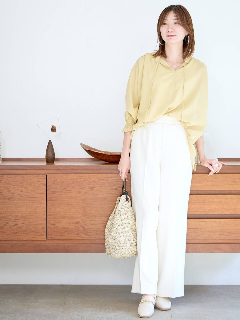 イエロー系のシャツ/ブラウス、ホワイト系のパンプスを着用したレディースの春コーディネートの1枚目の写真