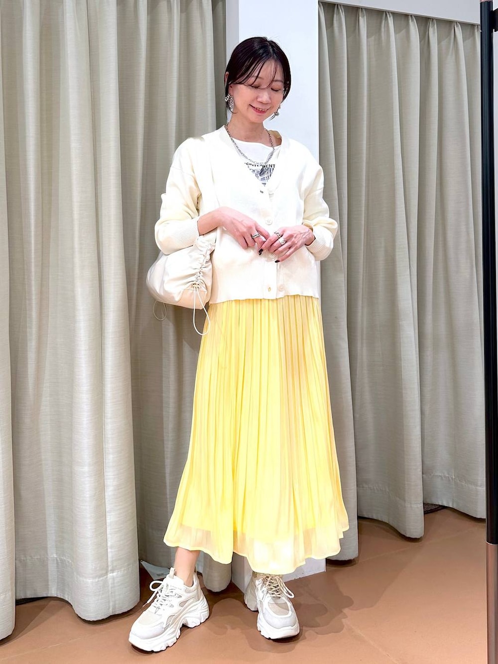 イエロー系のスカート、ホワイト系のカーディガン/ボレロ、ホワイト系のTシャツ/カットソーを着用したレディースの冬コーディネートの1枚目の写真