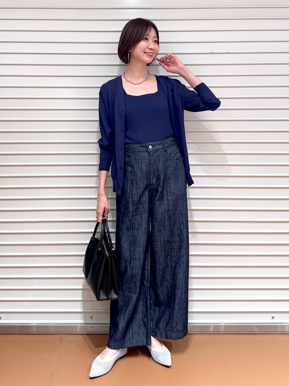 シルバー系のパンプス、ブルー系のデニムパンツ、ブラック系のショルダーバッグを着用したレディースの夏コーディネートの1枚目の写真