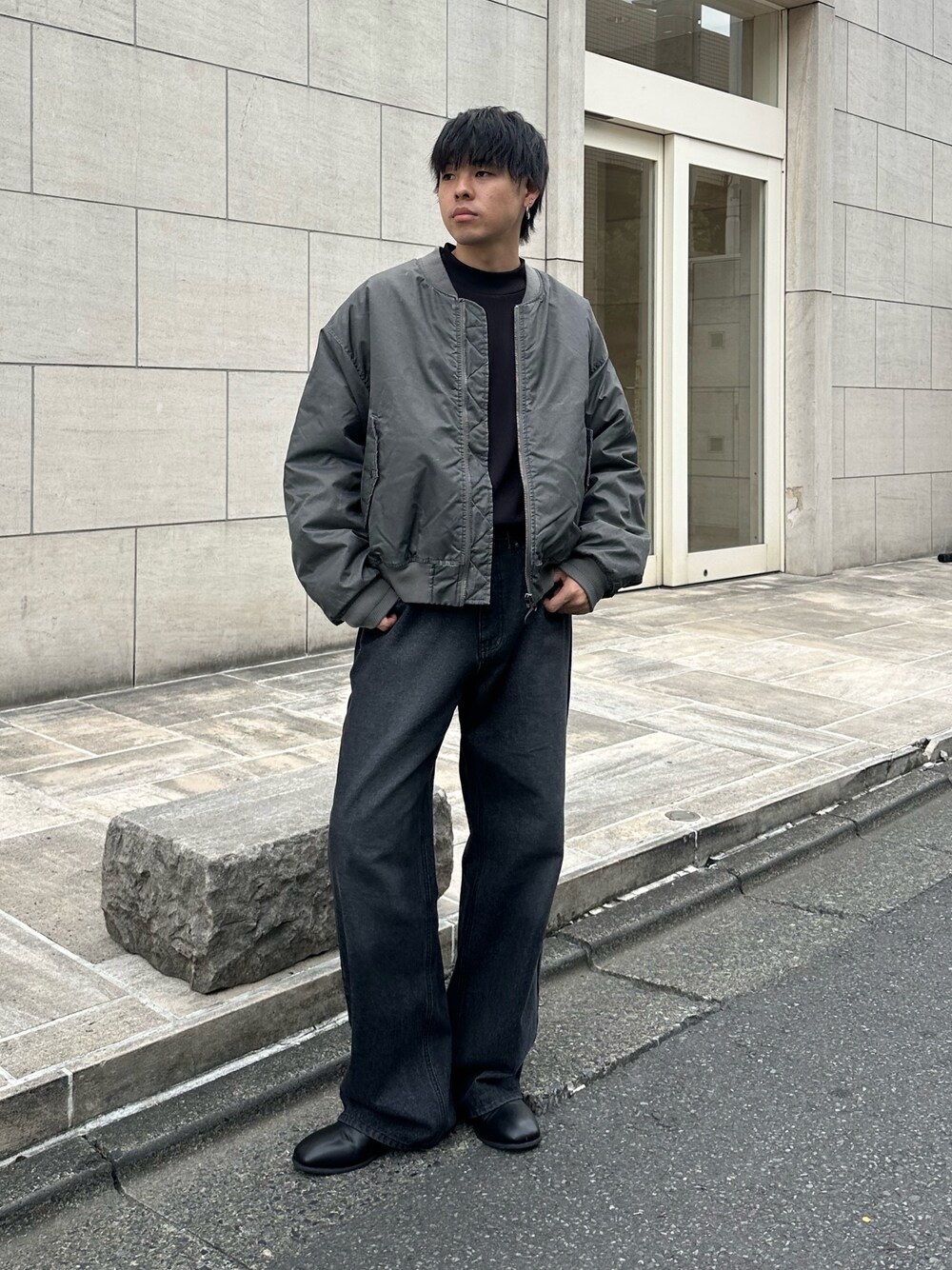 グレー系のブルゾン、ブラック系のTシャツ/カットソー、ブラック系のデニムパンツを着用したメンズの秋コーディネートの1枚目の写真