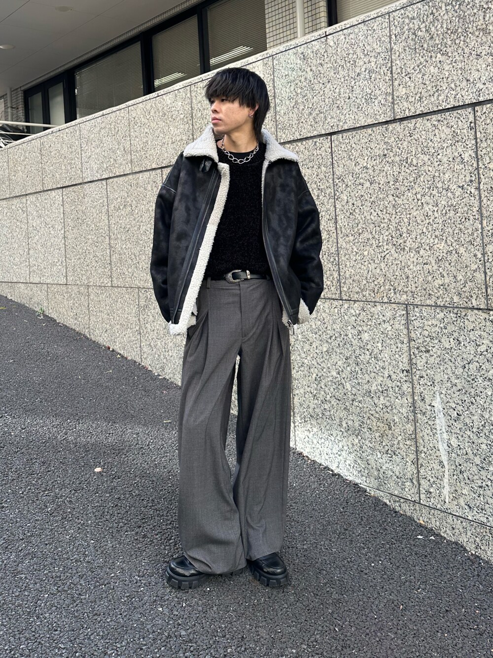 ブラック系のムートンコート、ブラック系のTシャツ/カットソー、グレー系のスラックスを着用したメンズの冬コーディネートの1枚目の写真