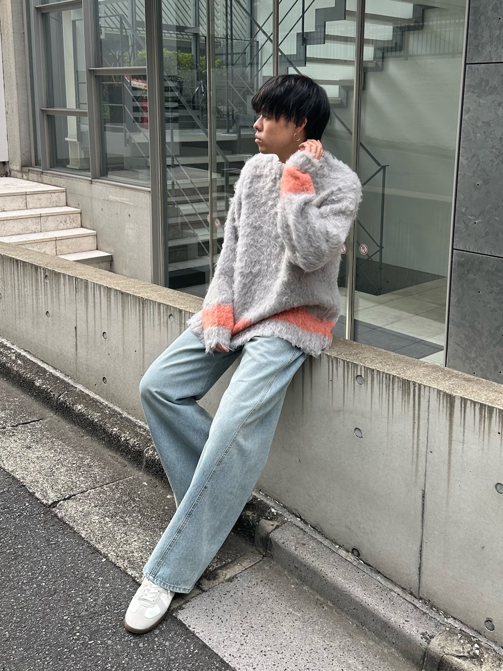 グレー系のニット/セーター、ブルー系のデニムパンツ、ホワイト系のスニーカーを着用したメンズの秋コーディネートの1枚目の写真