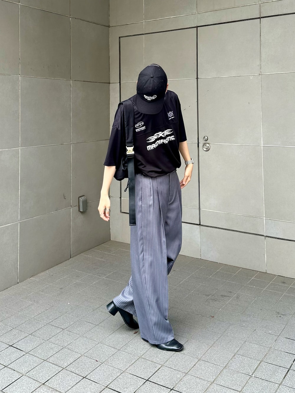 ブラック系のTシャツ/カットソー、ブラック系のショルダーバッグ、ブルー系のキャップを着用したメンズの夏コーディネートの1枚目の写真