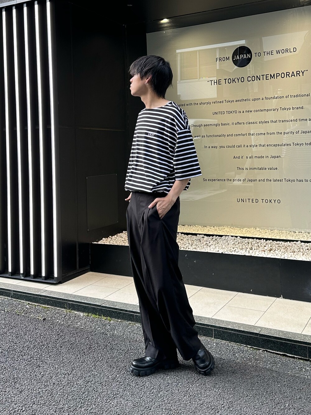 ブラック系のTシャツ/カットソー、ブラック系のスラックスを着用したメンズの春コーディネートの1枚目の写真