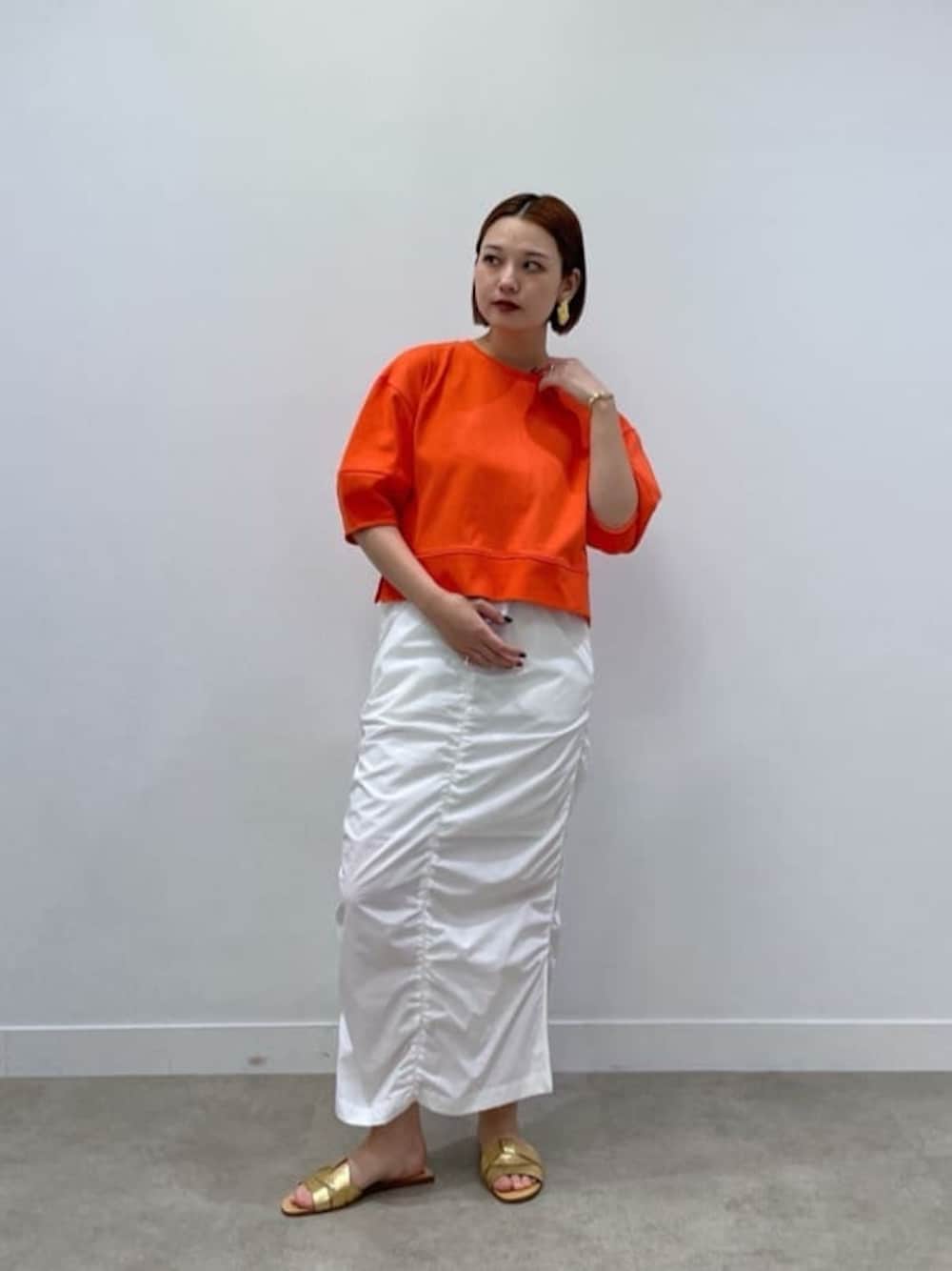 オレンジ系のTシャツ/カットソー、ホワイト系のスカートを着用したレディースの春コーディネートの1枚目の写真