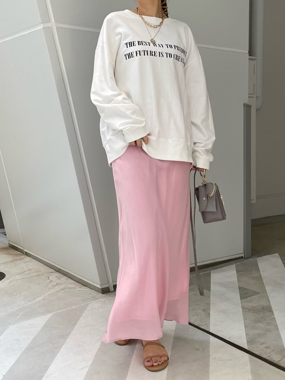 グレー系のショルダーバッグ、ピンク系のスカート、ホワイト系のTシャツ/カットソーを着用したレディースの春コーディネートの1枚目の写真