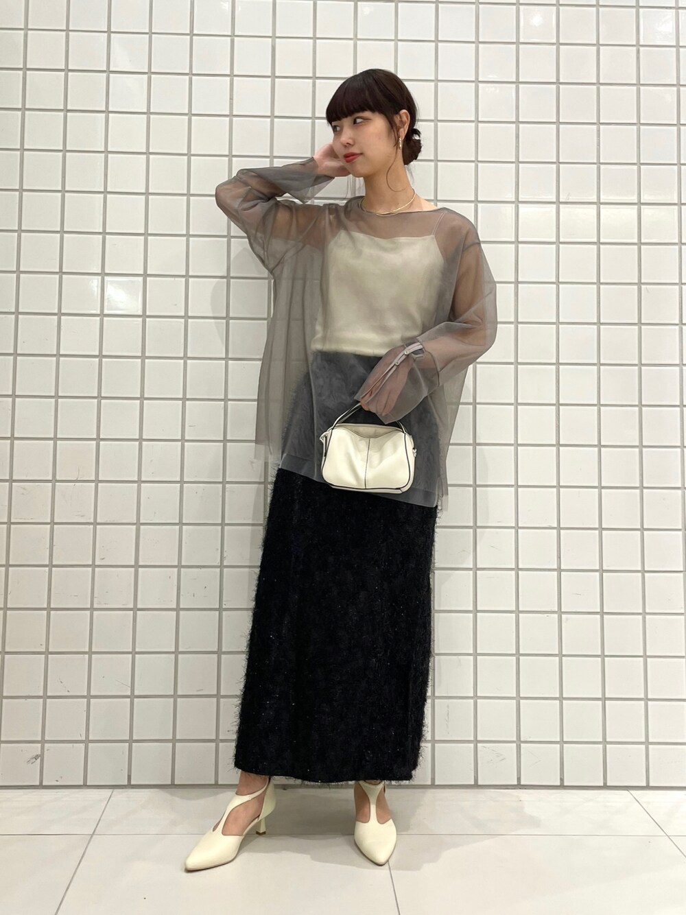 ホワイト系のパンプス、ブラック系のスカート、シルバー系のショルダーバッグを着用したレディースの春コーディネートの1枚目の写真