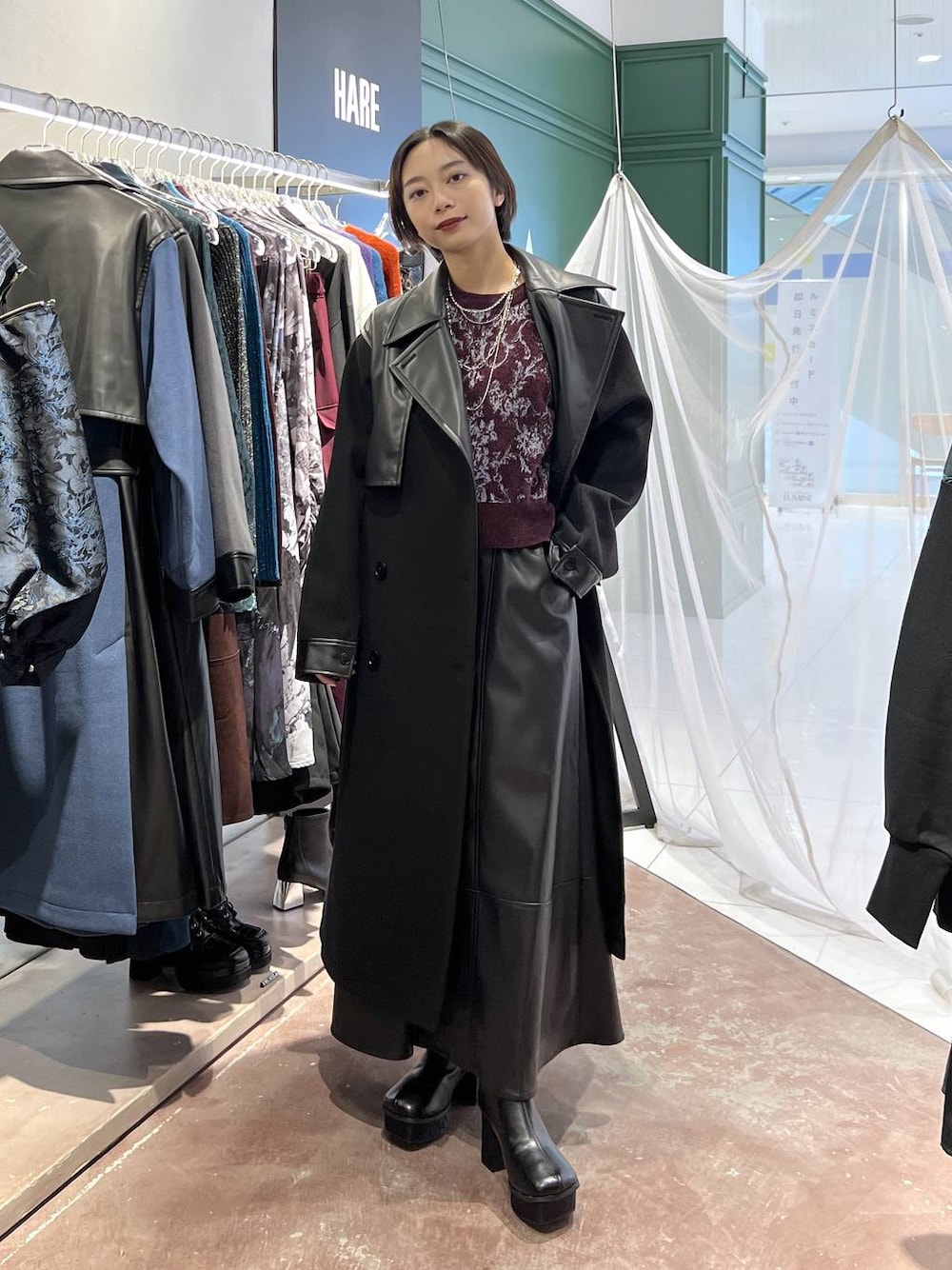 ブラック系のチェスターコート、レッド系のニット/セーター、ブラック系のブーツを着用したレディースの秋コーディネートの1枚目の写真