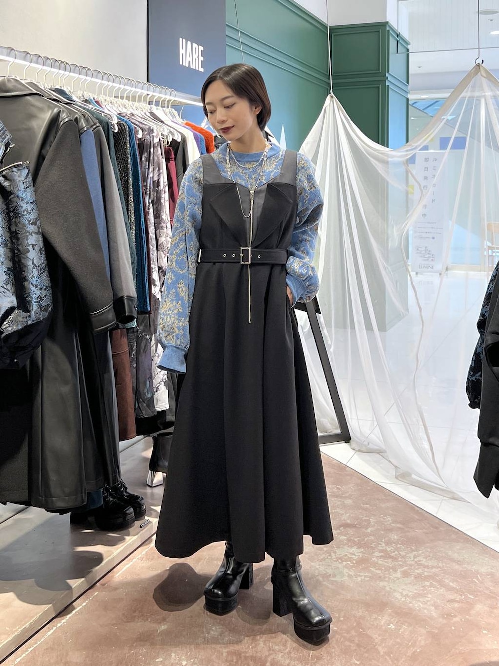 ブルー系のニット/セーター、ブラック系のブーツ、ブラック系のワンピースを着用したレディースの秋コーディネートの1枚目の写真