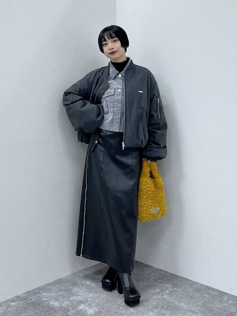 ブラック系のブーツ、イエロー系のショルダーバッグ、ブラック系のスカートを着用したレディースの秋コーディネートの1枚目の写真