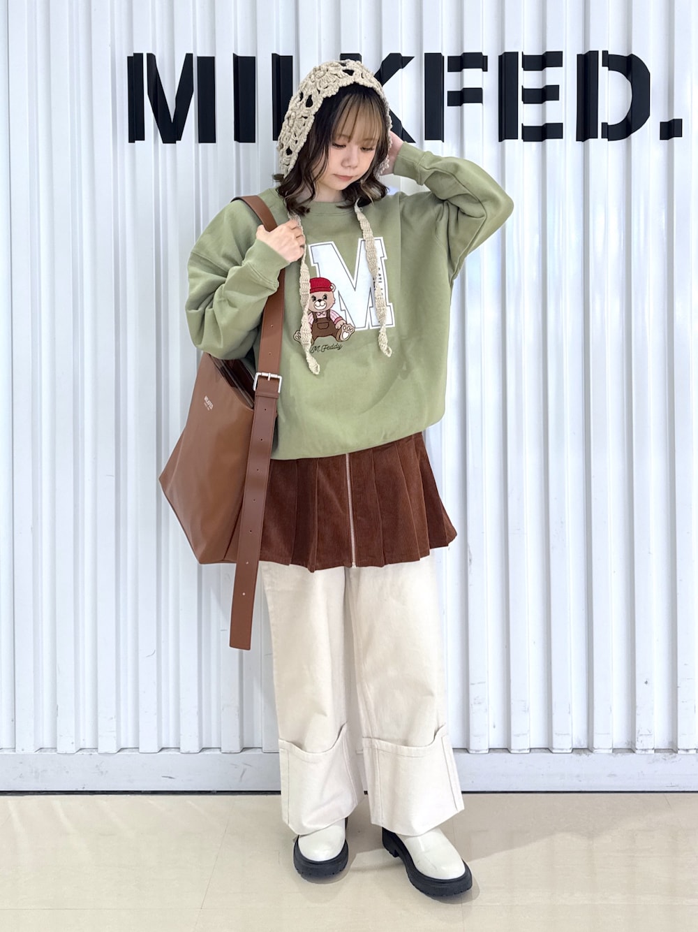 ホワイト系のデニムパンツ、グリーン系のスウェット、ブラウン系のショルダーバッグを着用したレディースの冬コーディネートの1枚目の写真