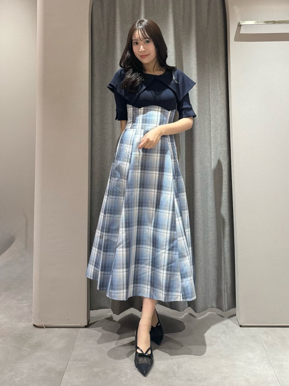 ブルー系のワンピース、ブラック系のパンプスを着用したレディースの春コーディネートの1枚目の写真