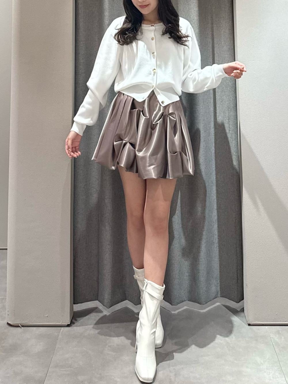 ホワイト系のカーディガン/ボレロ、ブラウン系のスカート、ホワイト系のブーツを着用したレディースの春コーディネートの1枚目の写真