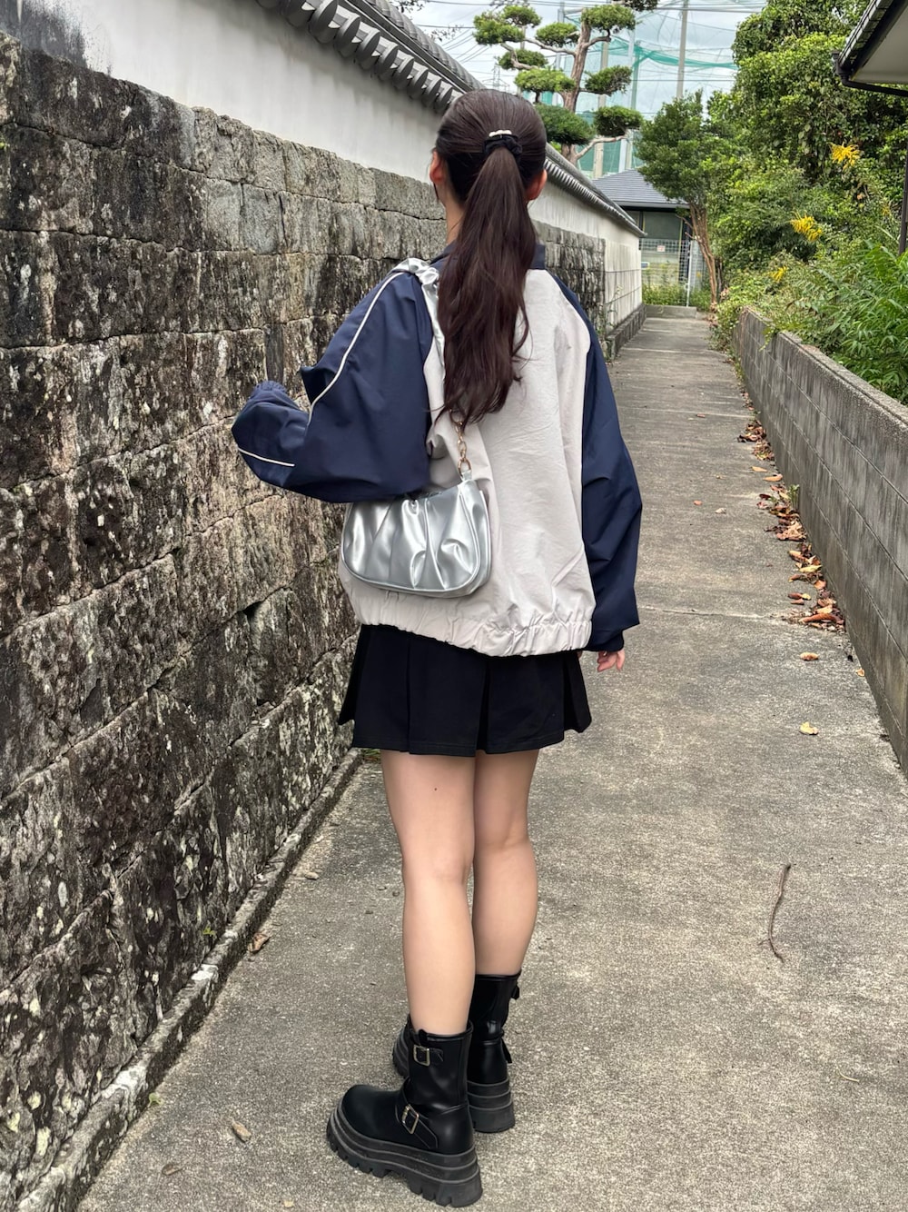 グレー系のナイロンジャケット、シルバー系のハンドバッグ、ブラック系のデニムスカートを着用したレディースの秋コーディネートの1枚目の写真