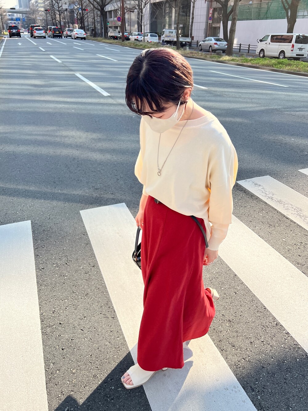 ホワイト系のニット/セーター、レッド系のスカート、ホワイト系のサンダルを着用したレディースの春コーディネートの2枚目の写真