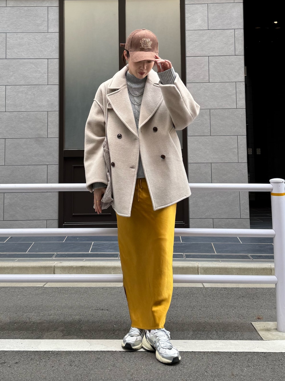 ベージュ系のピーコート、グレー系のニット/セーター、シルバー系のスニーカーを着用したレディースの秋コーディネートの1枚目の写真