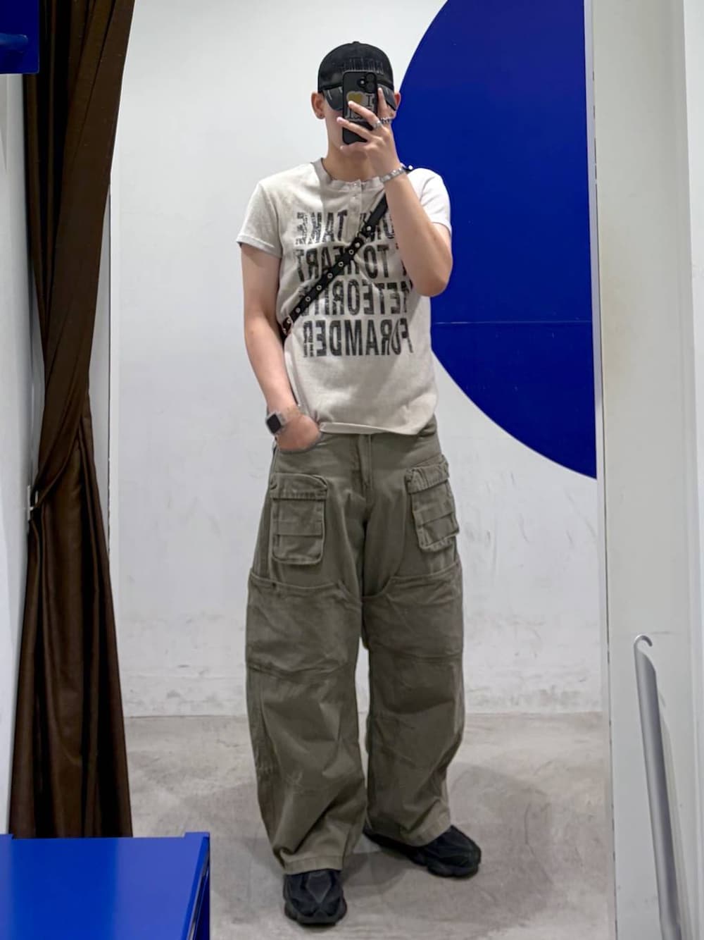 ベージュ系のTシャツ/カットソー、グリーン系のカーゴパンツ、ブラック系のショルダーバッグを着用したメンズの夏コーディネートの1枚目の写真