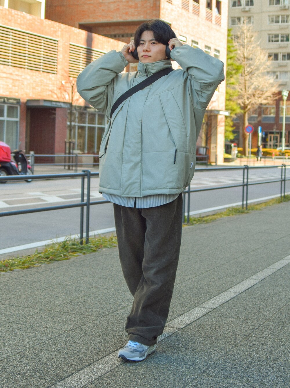 グレー系のスニーカー、グリーン系のショルダーバッグを着用したメンズの冬コーディネートの1枚目の写真