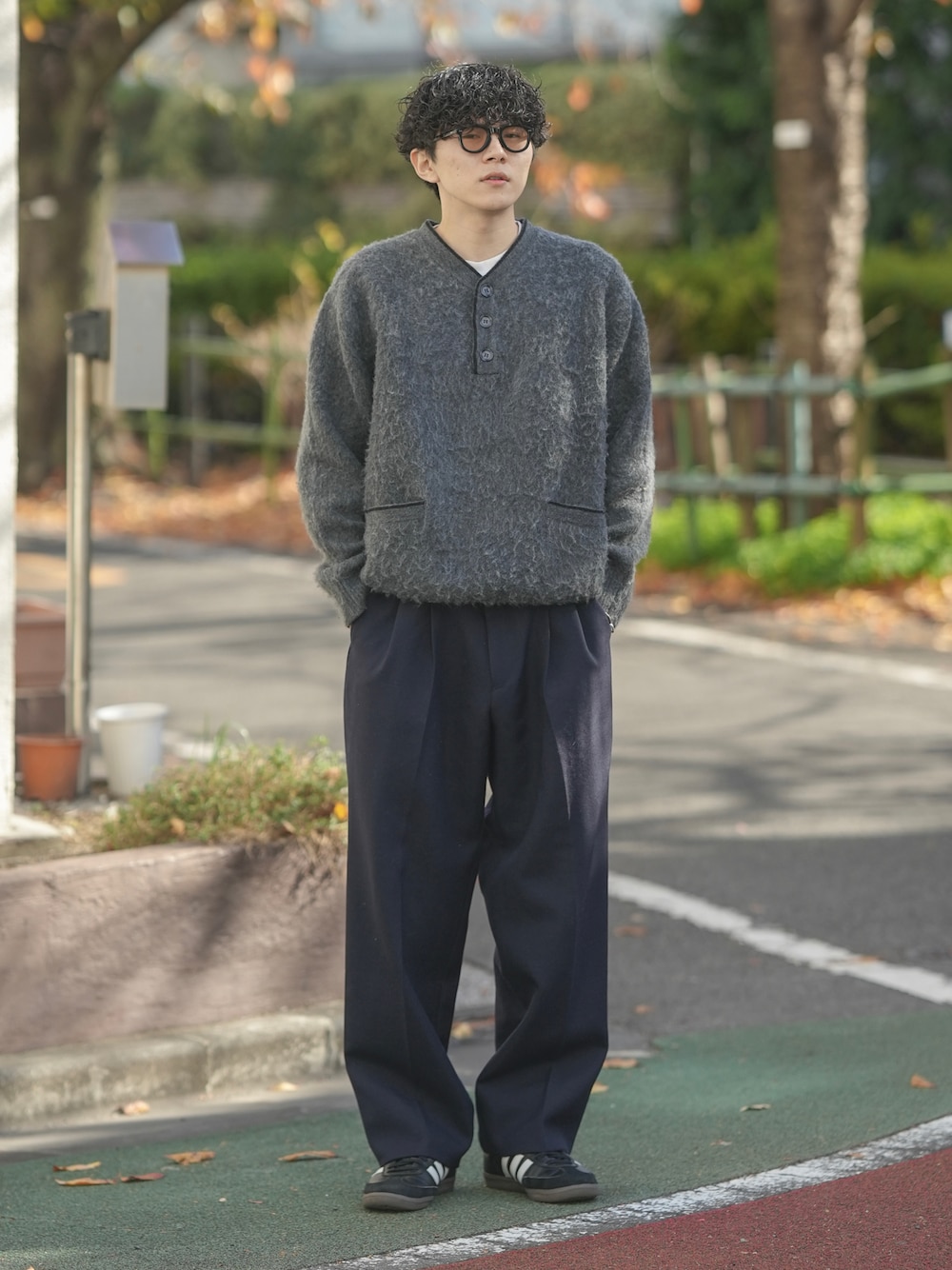 グレー系のニット/セーター、ブルー系のスラックス、ブラック系のスニーカーを着用したメンズの冬コーディネートの1枚目の写真