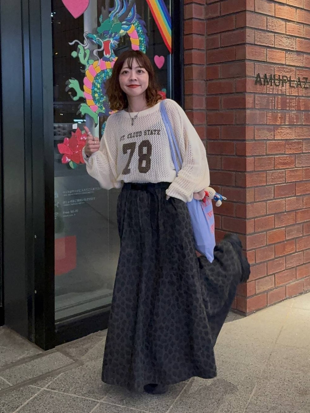 グレー系のスカート、ブラック系のスニーカー、ベージュ系のTシャツ/カットソーを着用したレディースの秋コーディネートの1枚目の写真