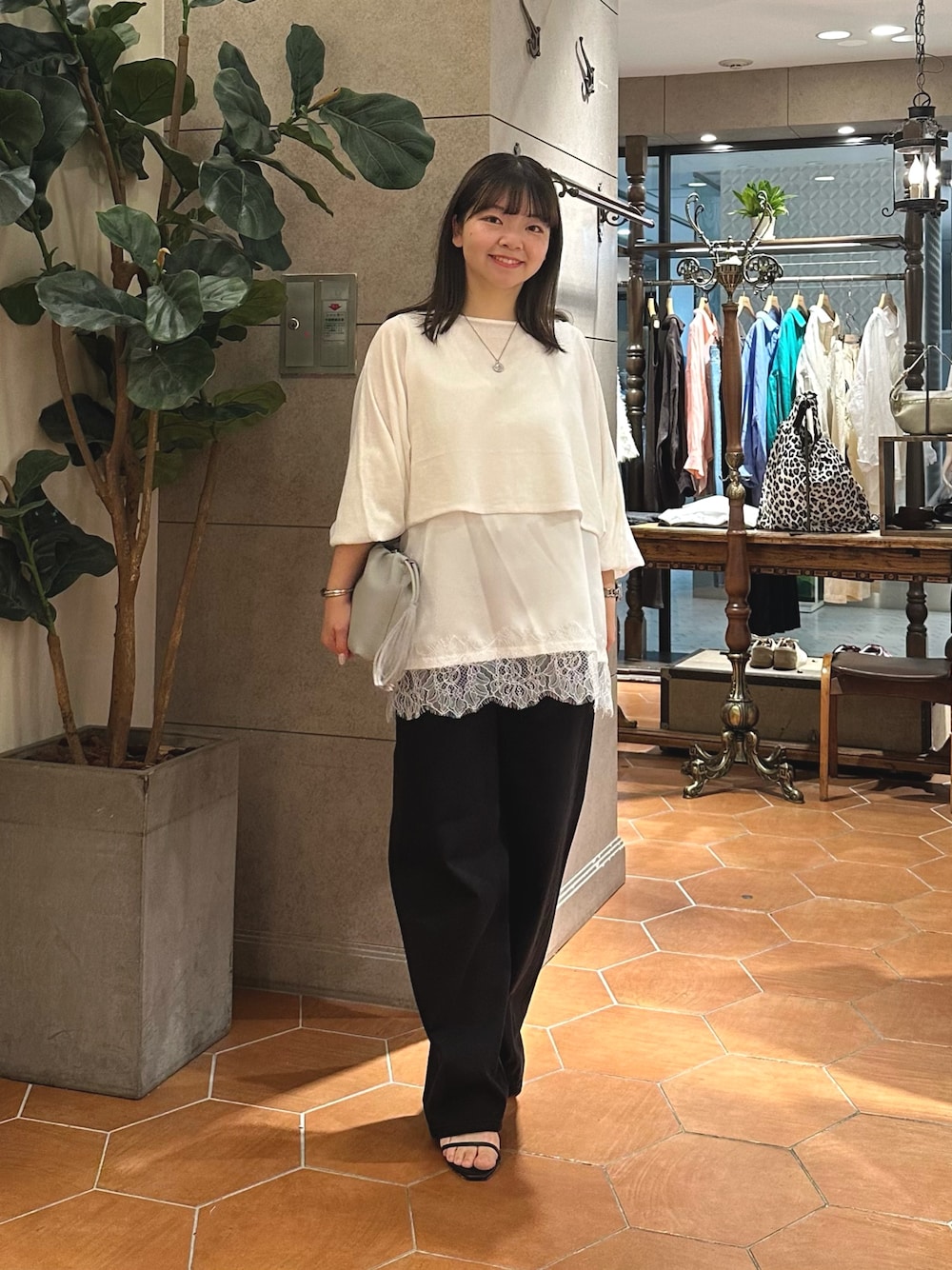 ホワイト系のニット/セーター、ホワイト系のシャツ/ブラウス、グレー系のショルダーバッグを着用したレディースの夏コーディネートの1枚目の写真