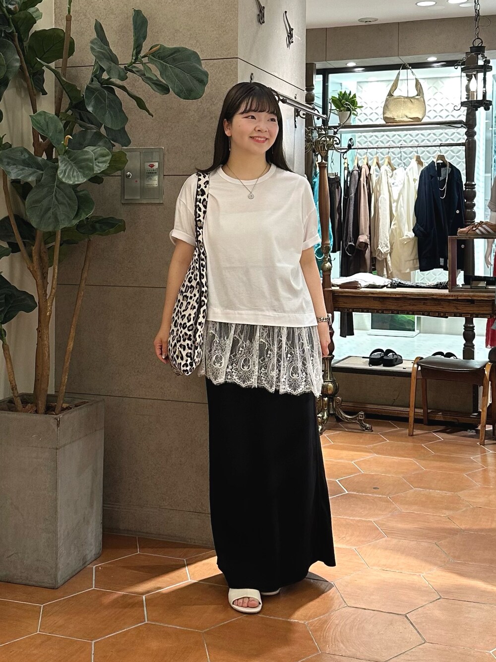 ホワイト系のTシャツ/カットソー、ベージュ系のトートバッグ、ブラック系のスカートを着用したレディースの夏コーディネートの1枚目の写真